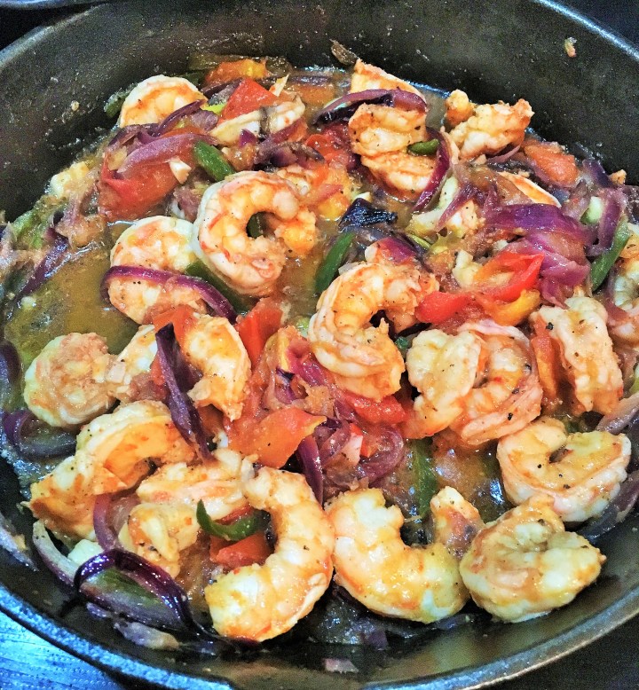A skillet full of shrimp and veggies for tacos.